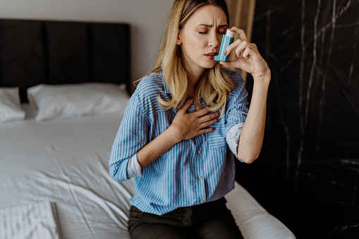 Young woman using her asthma inhaler