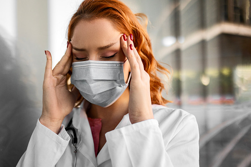 Serious female doctor with face mask outside