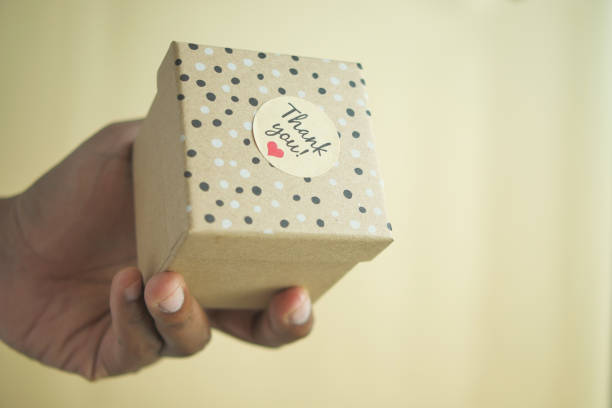 istock hand putting a thank you sticker on a gift box 1847756392