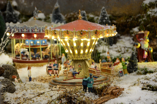 Christmas decoration: Illuminated merry-go-round in a snow landscape. Focus on the two figurines.