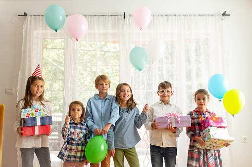Group of children having fun and playing with ballons on a indoors Birthday party