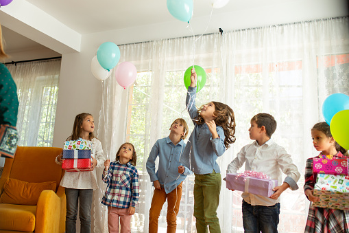 Group of children having fun and playing with ballons on a indoors Birthday party