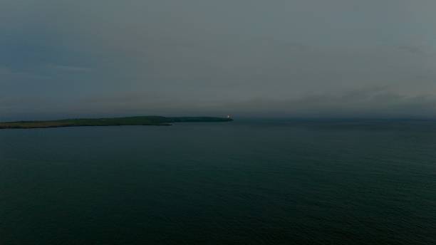 lighthouse flash at twilight over the sea - ireland landscape flash imagens e fotografias de stock
