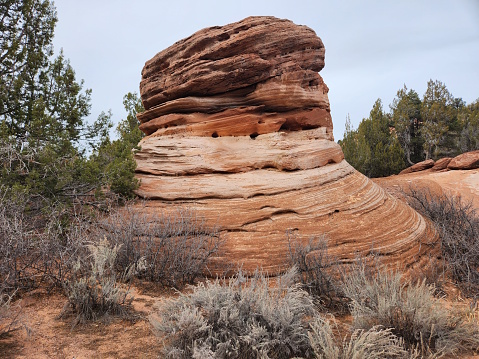 This photo showcases a unique rock formation that looks like a big thimble in southern Utah. The formation is made of red sandstone and is surrounded by desert flora and a blue sky. It is a natural wonder that attracts hikers and adventurers who want to explore the desert southwest.