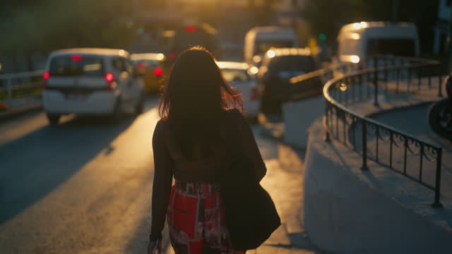 Rear view of multi-ethnic female tourist walking in street during sunset during her travel