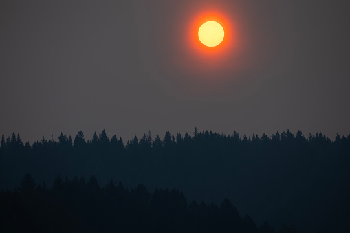 The sun rises over the horizon as the smoke from a nearby forest fire lingers in the air in Alberta, Canada.