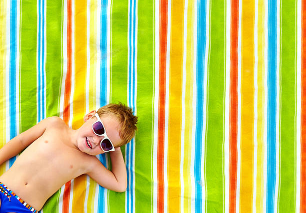 happy kid sunbathing on colorful blanket happy kid sunbathing on colorful blanket beach mat stock pictures, royalty-free photos & images