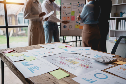 Meeting of hardworking businesspeople work together as a team by presenting graphs. and charting the work of each department, presenting and discussing the report together in the meeting.