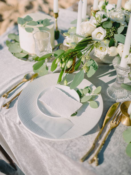 Elegant table setting with a paper card decorated with eucalyptus branches close up. Romantic table with paper invitation card. Wedding Mockup.