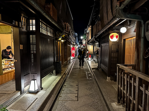Kyoto, Japan - 07.11.2023. Night time street view of Gion area in Kyoto, Japan. Narrow alley street in Gion district at night with people and illuminated restaurant building with menu. Japanese lanterns, japanese medieval architecture
