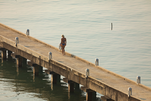 Thailand - Jan 15, 2020: A woman, a Western tourist, strolls along a concrete pier on the island of Koh Chang, Thailand