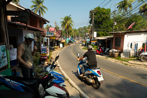Thailand - Jan 15, 2020: Road and motorbikes in an inhabited area of the west of the island of Koh Chang, in the Gulf of Thailand, near Lonely Beach