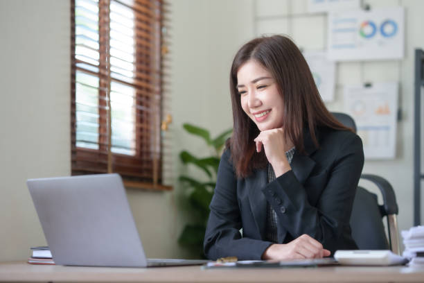 istock Smiling and attractive asian businesswoman enjoying working using laptop computer at office. 1847830118
