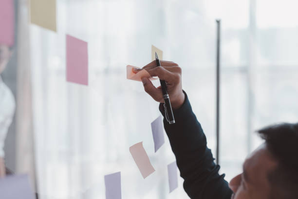 istock Businessman writing something on sticky notes while working on a business plan at office. 1847834424
