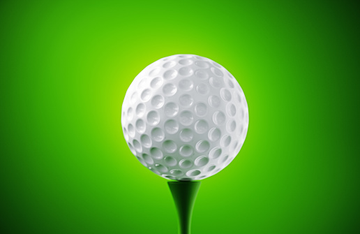 White golf ball on green background. Horizontal composition.