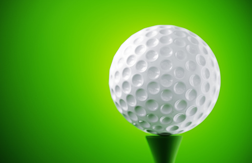 White golf ball on green background. Horizontal composition.