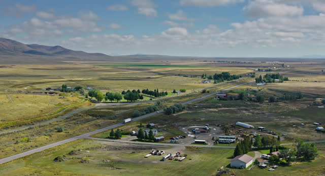 Truck and Cars on Highway Passing Farmland in Butte County, Idaho - Aerial