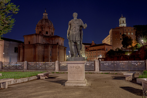 Night Shot Julius Caesar statue with church of Saint Luca e Martina on the background - a bronze copy of the statue in the Capitol