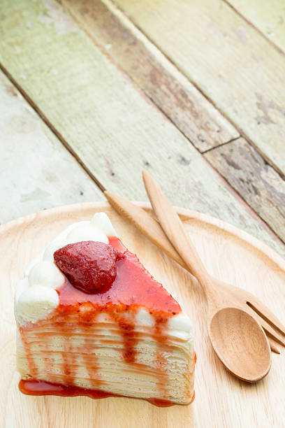 Crepe cake with strawberry sauce on wooden plate stock photo