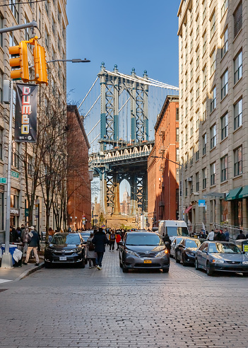 Brooklyn, New York, USA - February 11, 2023: View of under Manhattan Bridge from the Dumbo neighborhood with its brick buildings where people walk on a winter day