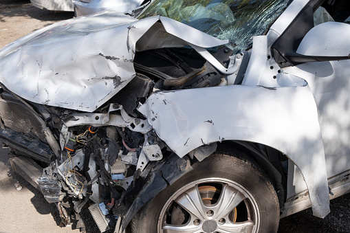 car after an accident, severed wires dangle from the front of damaged vehicle, illustrating the aftermath of the collision.