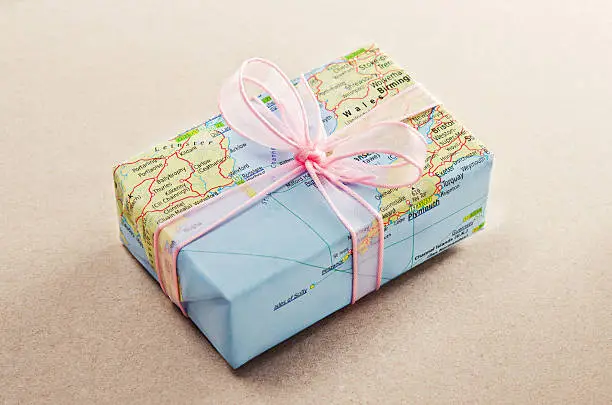 Photo of A bon voyage gift wrapped with map paper and pink bow