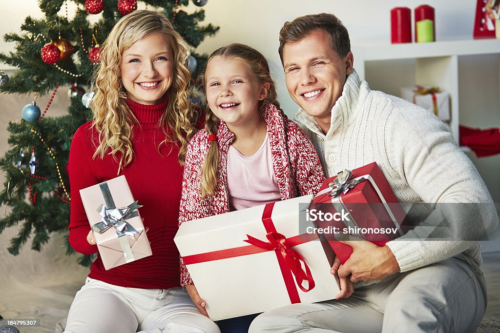 Family with gifts Portrait of happy family with giftboxes looking at camera on Christmas day Adult Stock Photo