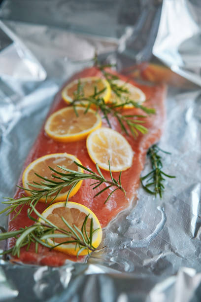 Preparing trouts with lemons butter and green dill. Close up.