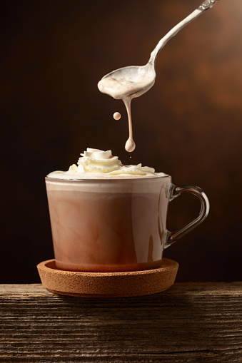 Hot chocolate with whipped cream on a brown background. Copy space.
