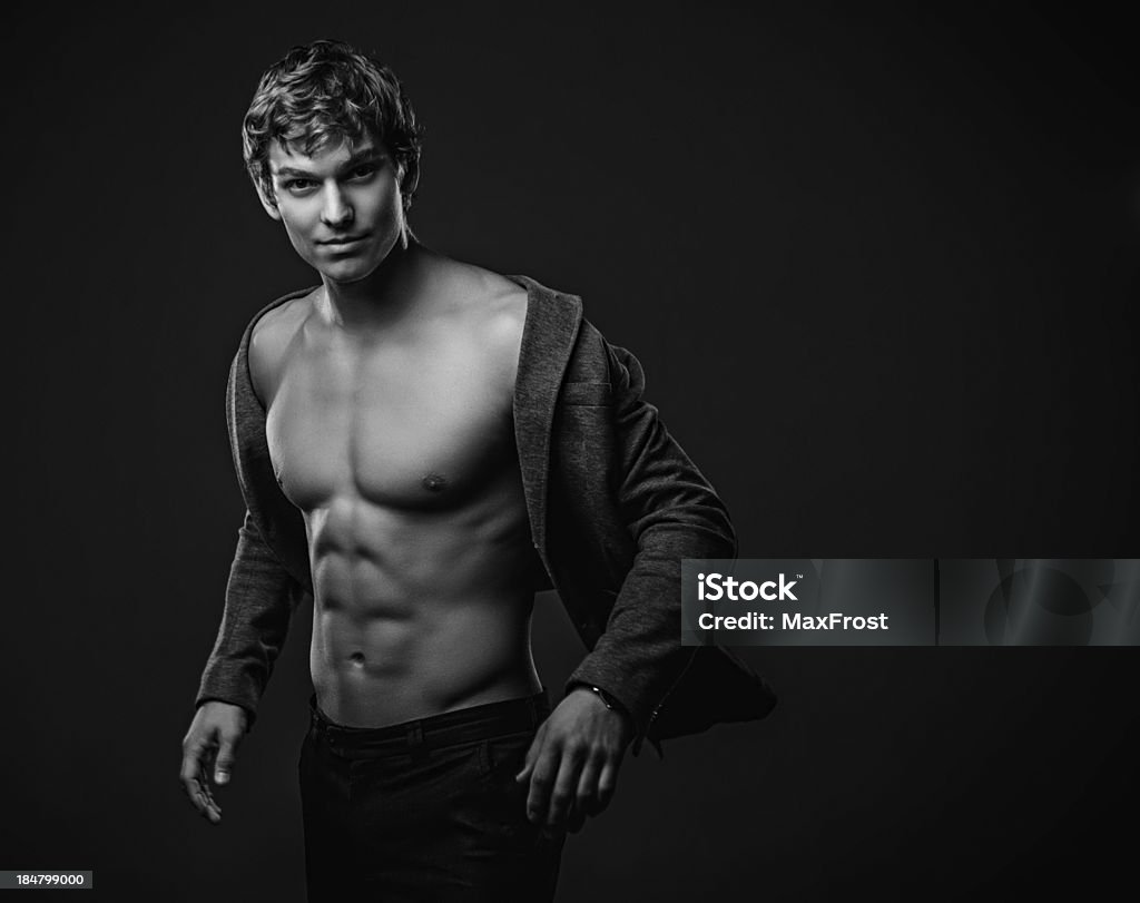 Young handsome macho man with muscle abdominal and open jacket Young handsome macho man with muscle abdominal and open jacket. Black and white studio shoot Abdominal Muscle Stock Photo