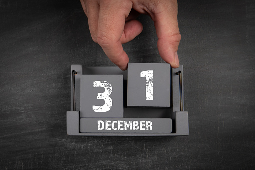 31 December. Wooden calendar on dark chalkboard texture background.