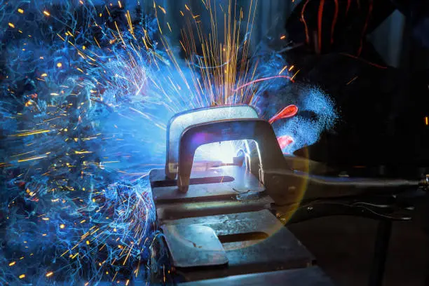Photo of During welding using argon gas, sparks created by welding process produce smoke in a factory