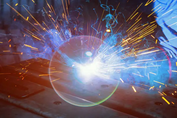 Photo of During welding, sparks are produced as argon gas is used to steel that smoke in a factory