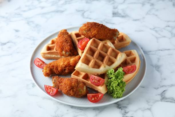 istock Tasty Belgian waffles served with fried chicken, tomatoes and lettuce on white marble table 1848020804