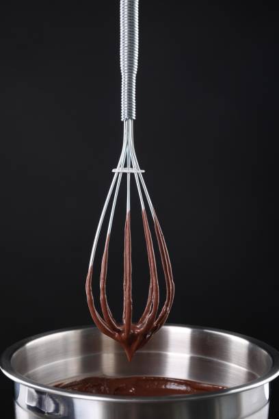 istock Chocolate cream flowing from whisk into bowl on black background 1848028216