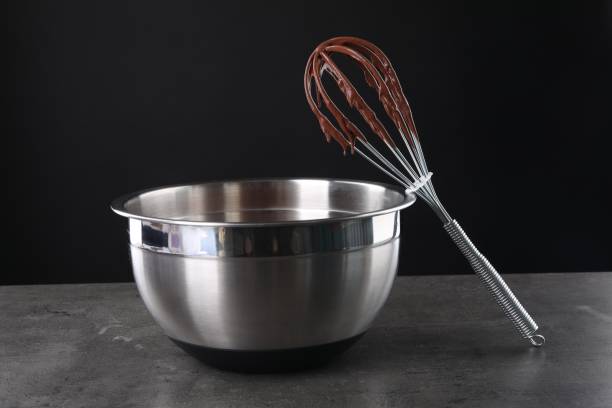 istock Bowl and whisk with chocolate cream on grey table against black background 1848028718