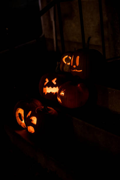 illuminated jack-o'-lanterns, each one telling a unique tale with spooky and cute faces carved into the pumpkins, lit up by the warm glow of candles for Halloween night.