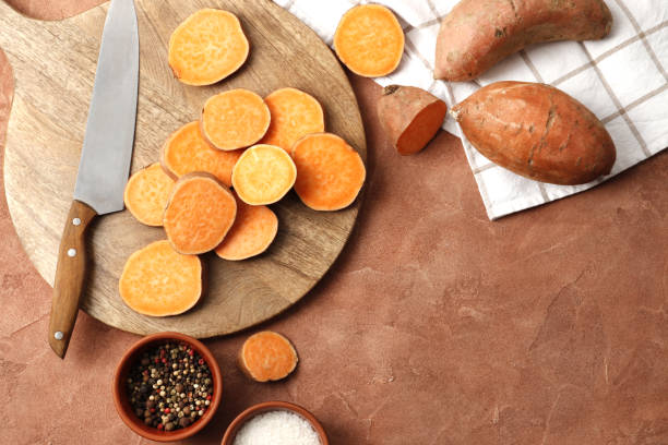 istock Composition of Fresh ripe sweet potatoes, spices, kitchenware on a colored table background 1848048540