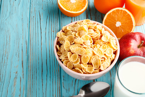 Healthy breakfast of cornflakes and fruits on a blue wooden background. Place for text. Top view.