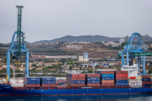 Container ship being loaded at Marseille container port with Marseille sign in background in Marseille, France on 27 August 2023