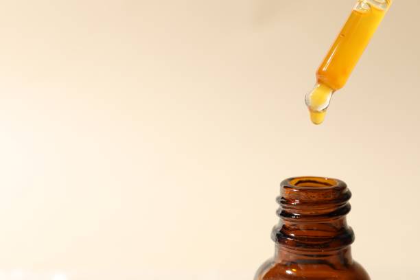 istock Dripping cosmetic serum from pipette into bottle on beige background, closeup. Space for text 1848088706
