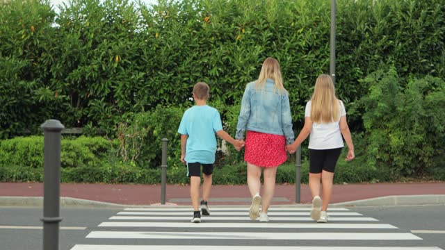 a girl with two children crosses the road at a pedestrian crossing
