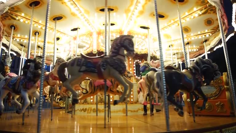 Christmas carousel with mechanical horses spinning at night in winter with some children and adults and lots of lights.