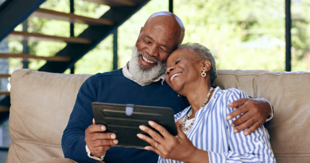 istock Tablet, hug and senior couple on a sofa for web communication, network or chat at home. Digital, app and old people embrace in living room with love, social media or streaming subscription in a house 1848099498