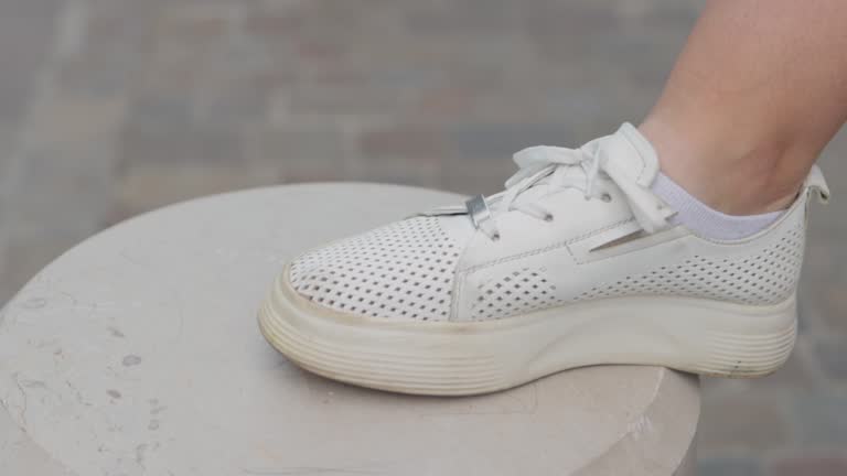 Close up of a young womans hand tying the laces on white sneakers. Outdoor exercise concept. High quality 4k footage