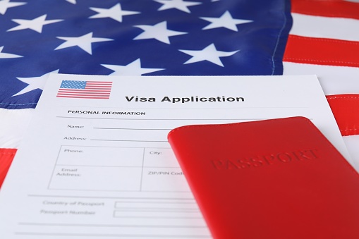 Immigration to USA. Visa application form and passport on flag, closeup