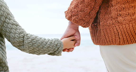 Couple, holding hands and ocean for love, care or support in trust, travel or outdoor getaway together. Closeup of man and woman touching in romance for unity, bonding or compassion on beach coast