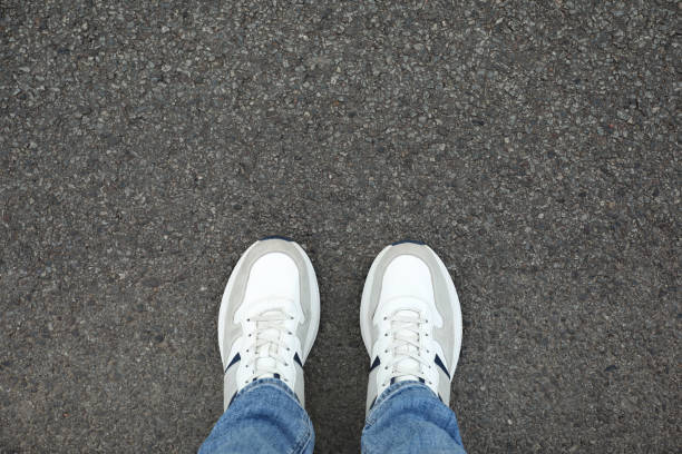 istock Man in sneakers standing on asphalt, top view. Space for text 1848155511