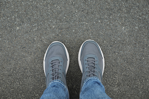 Man in sneakers standing on asphalt, top view