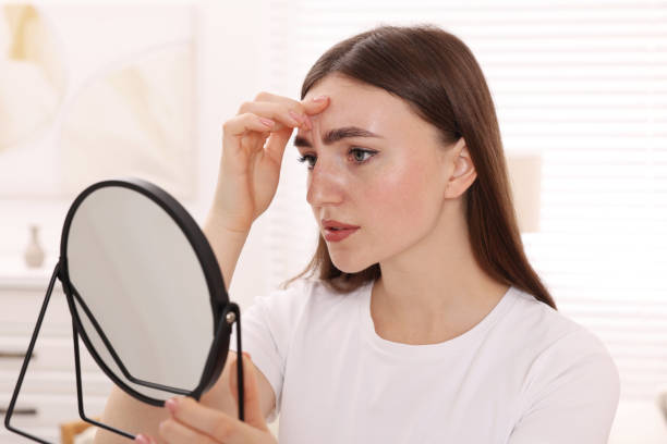istock Young woman with skin problem looking at mirror indoors 1848178184